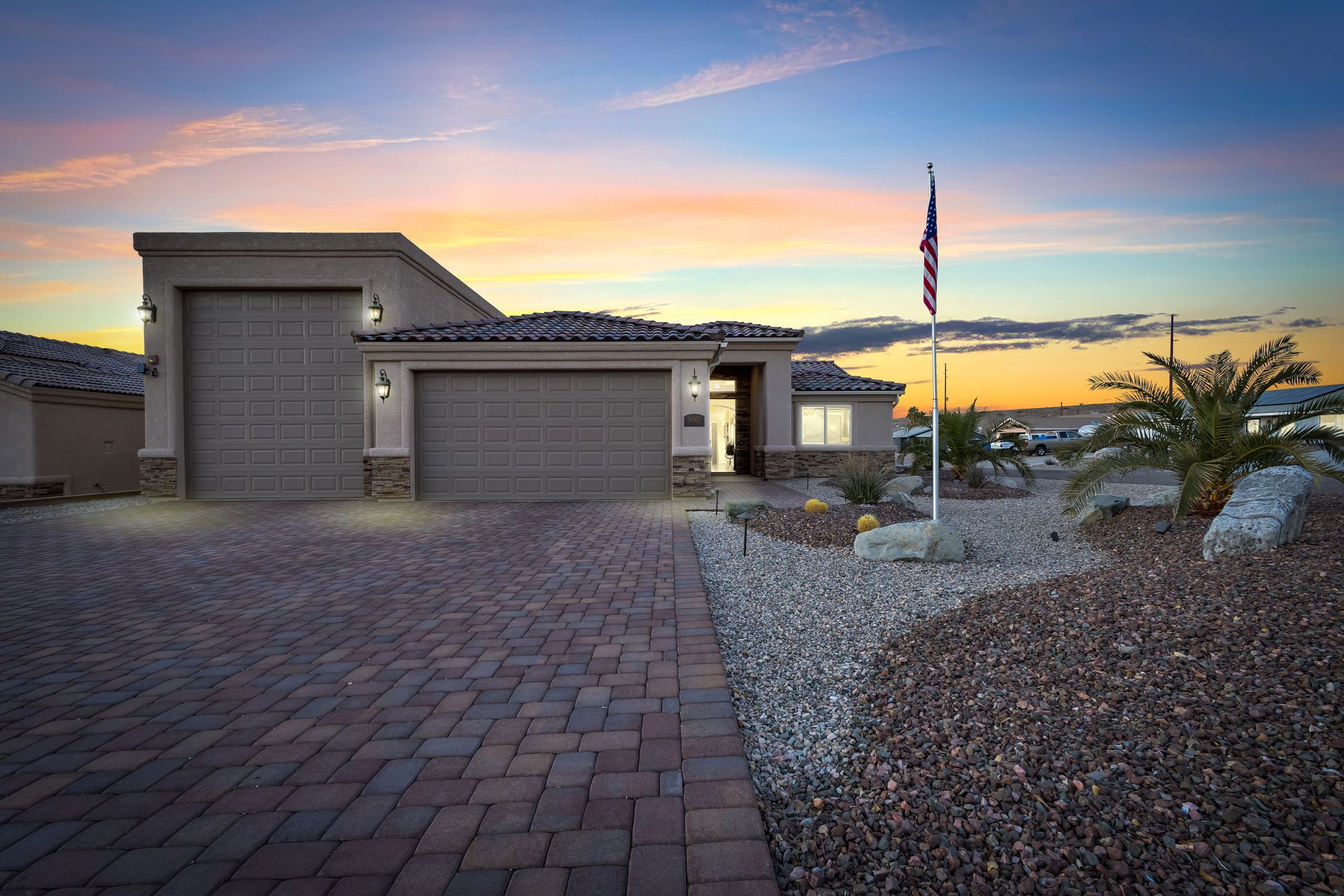 House exterior at dusk with paved driveway and American flag.