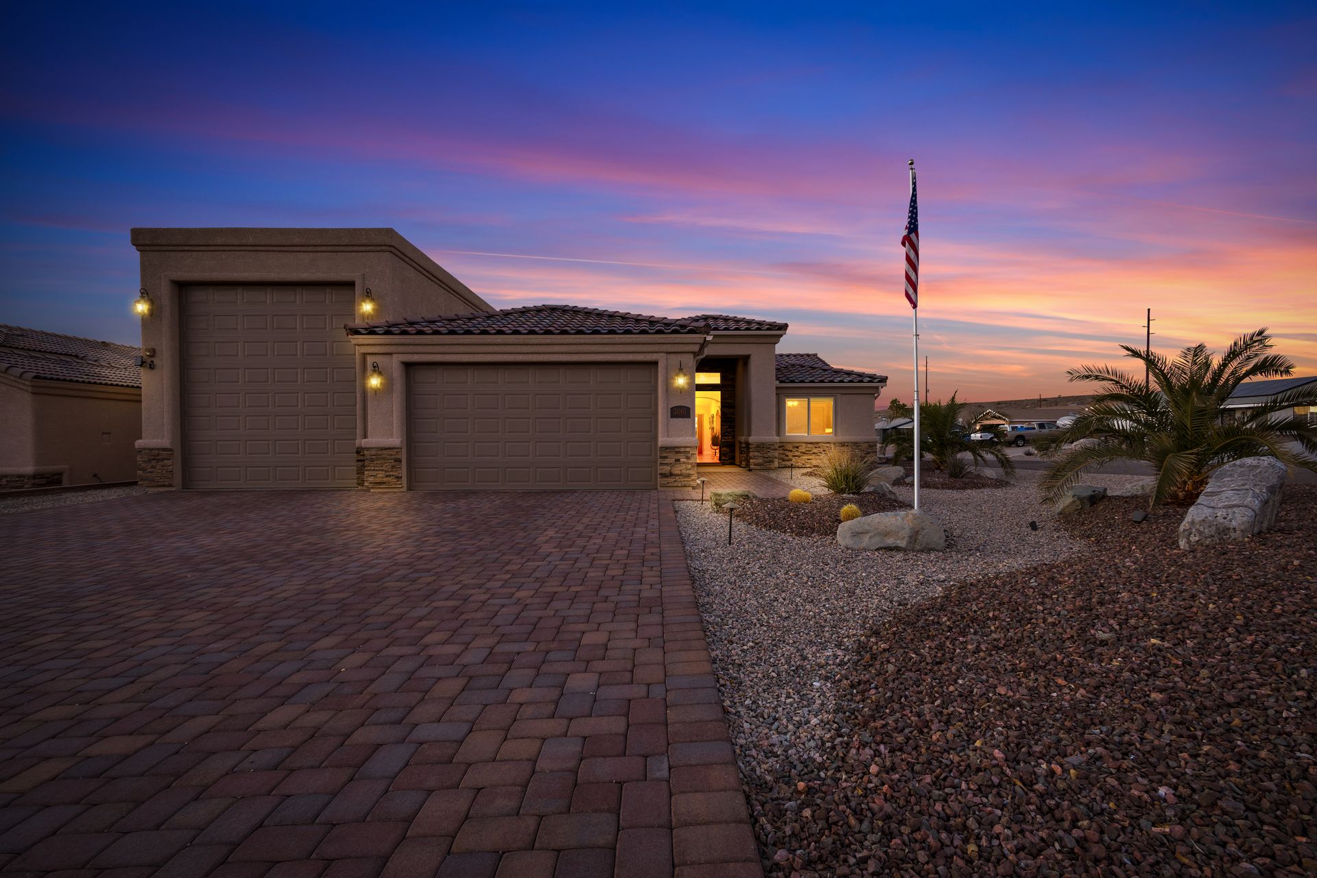 House exterior at sunset with a brick driveway and American flag.