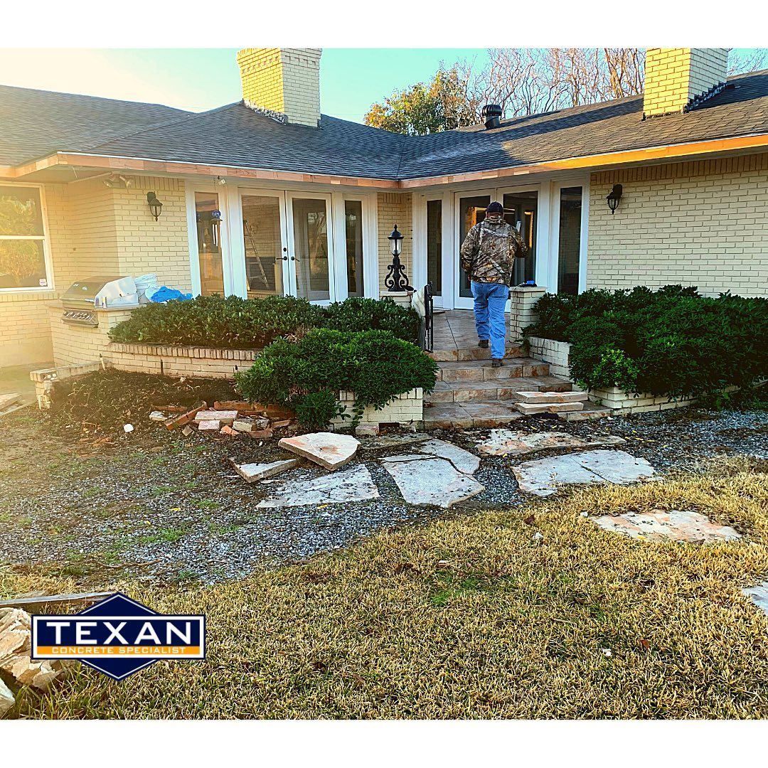 A man in a camo jacket is standing in front of a house.