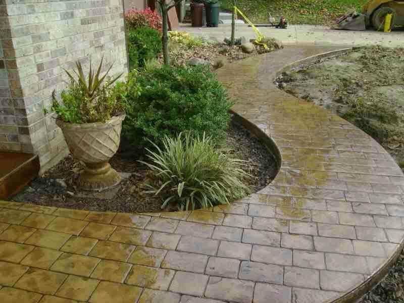 A brick walkway with a potted plant on the side of it.