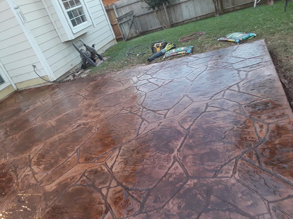 A concrete patio is being built in the backyard of a house.