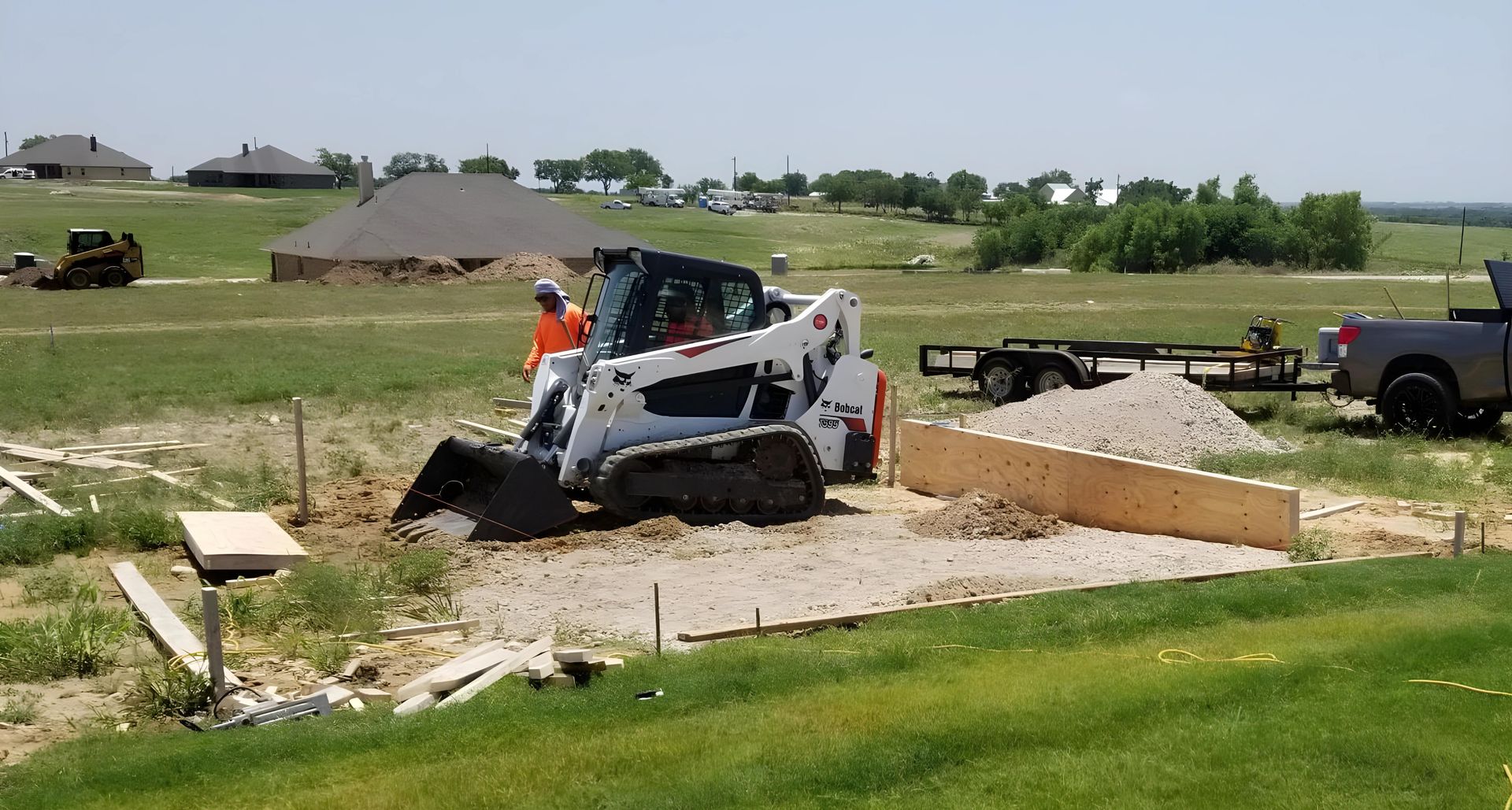 A bulldozer is moving dirt in a field next to a truck