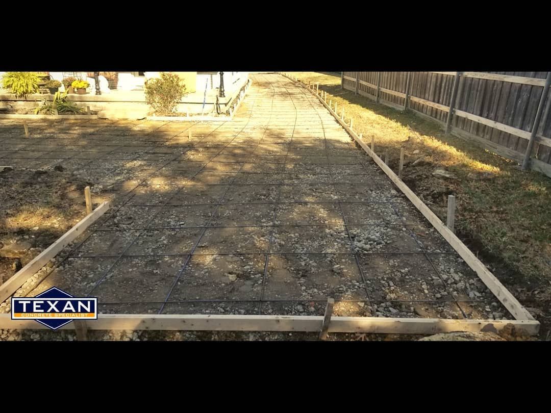 A concrete driveway is being built next to a wooden fence.