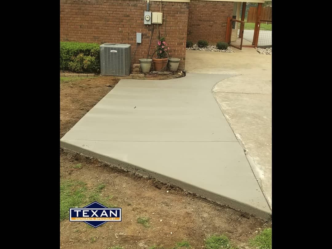 A concrete walkway is being built in front of a brick wall.
