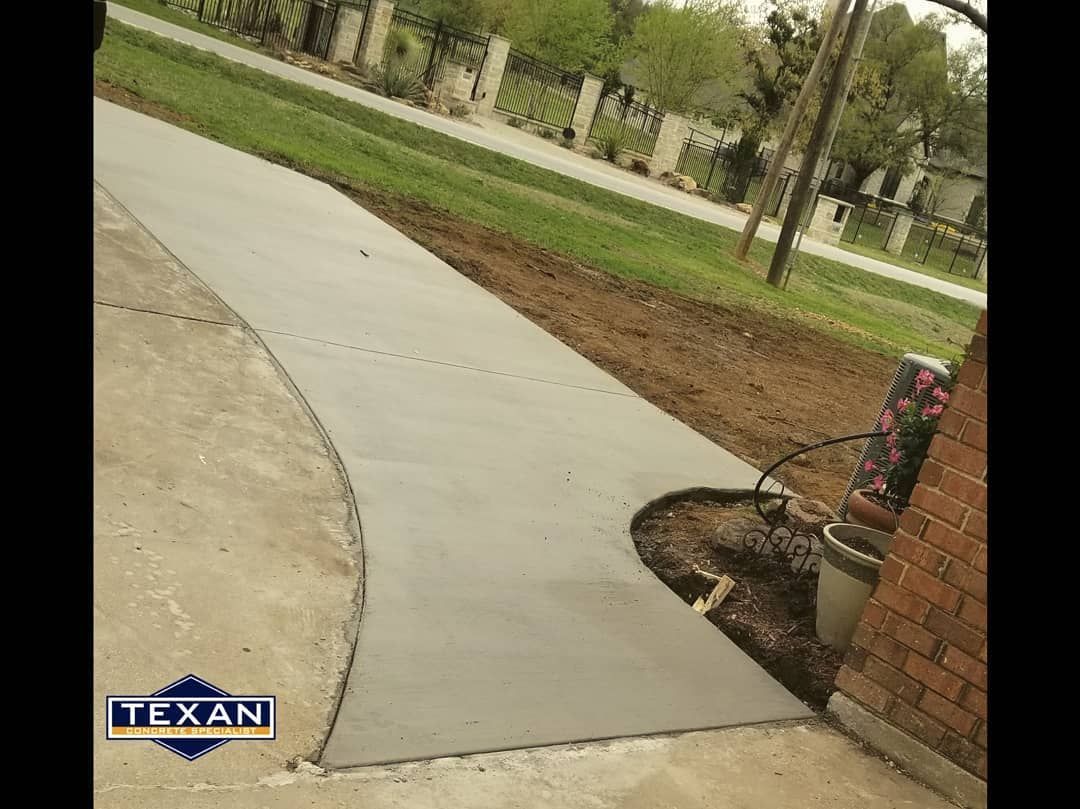 A concrete walkway is being built next to a brick building.