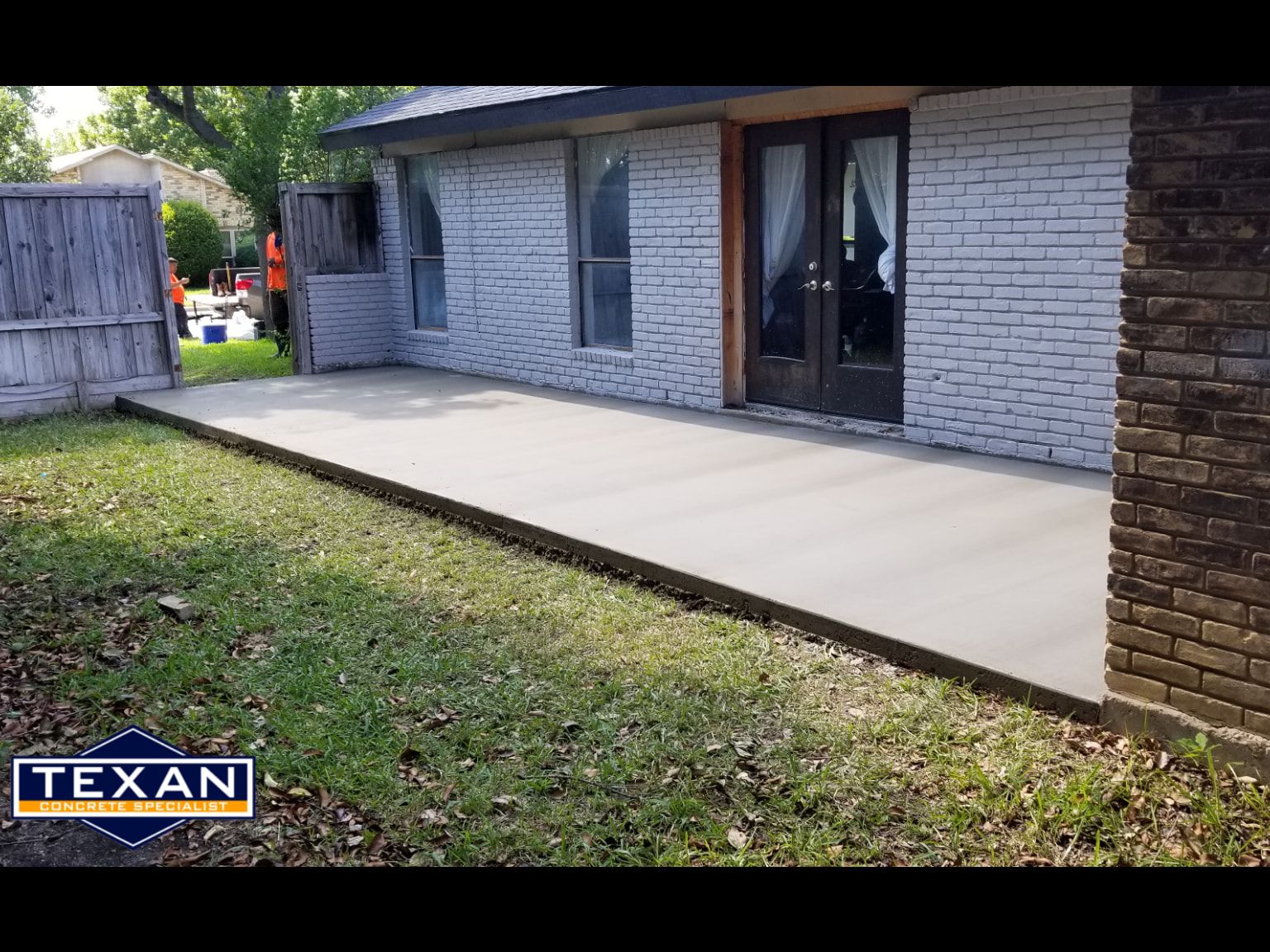 A brick house with a concrete patio in front of it.