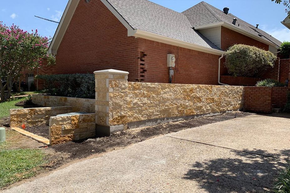 A brick house with a stone wall in front of it.