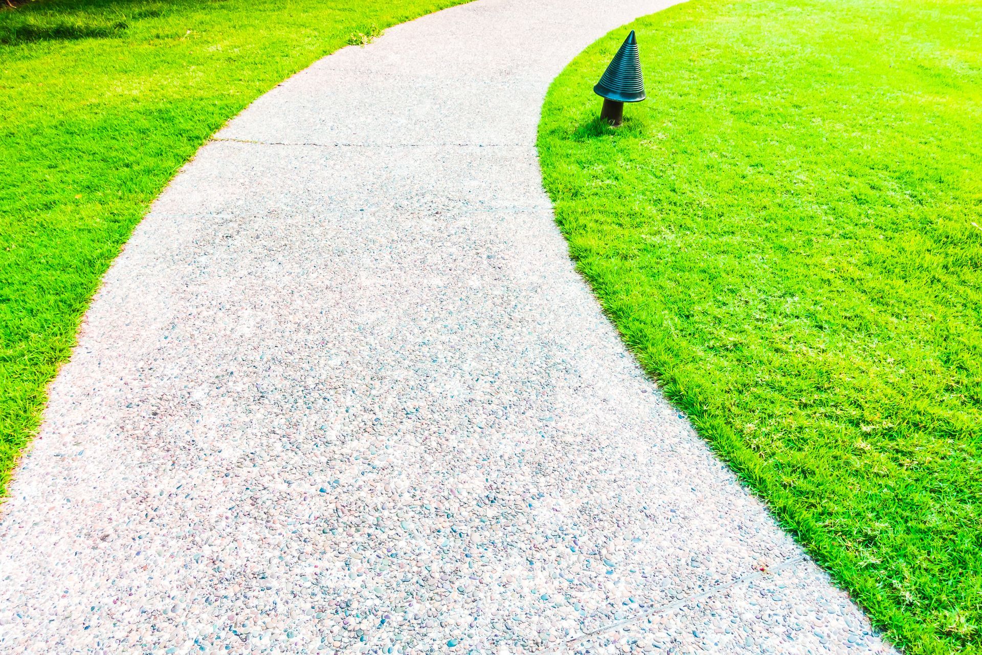 A concrete walkway going through a lush green field.