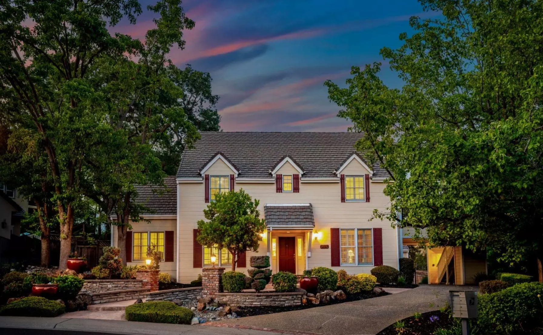 A white house with red shutters is lit up at night | Discover Homes for Sale in Rocklin, CA with Sonia Immers