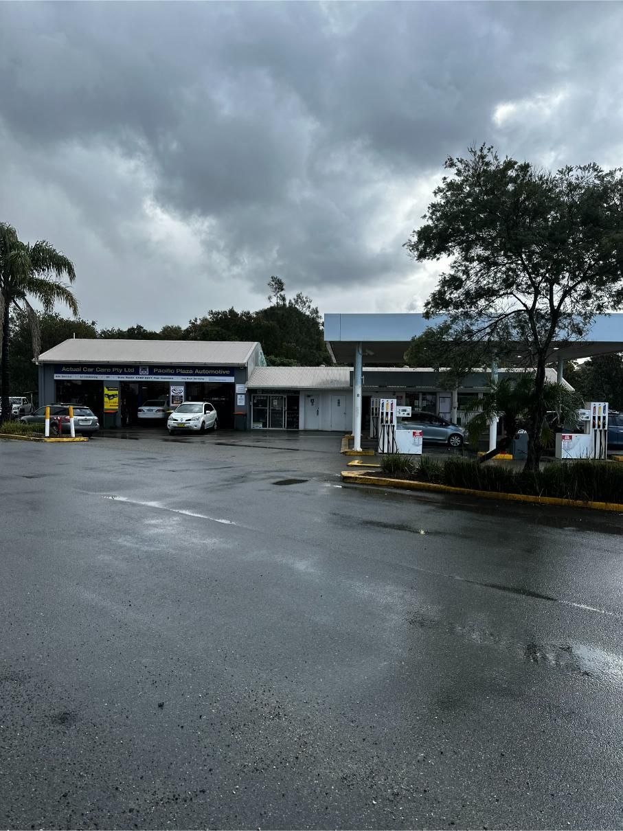 A Parking Lot With Cars Parked in Front of a Building on a Cloudy Day — Pacific Plaza Automotive in Port Macquarie, NSW
