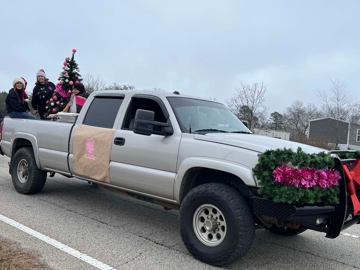 Silver pickup truck with people and Christmas trees decorated for a parade or holiday event