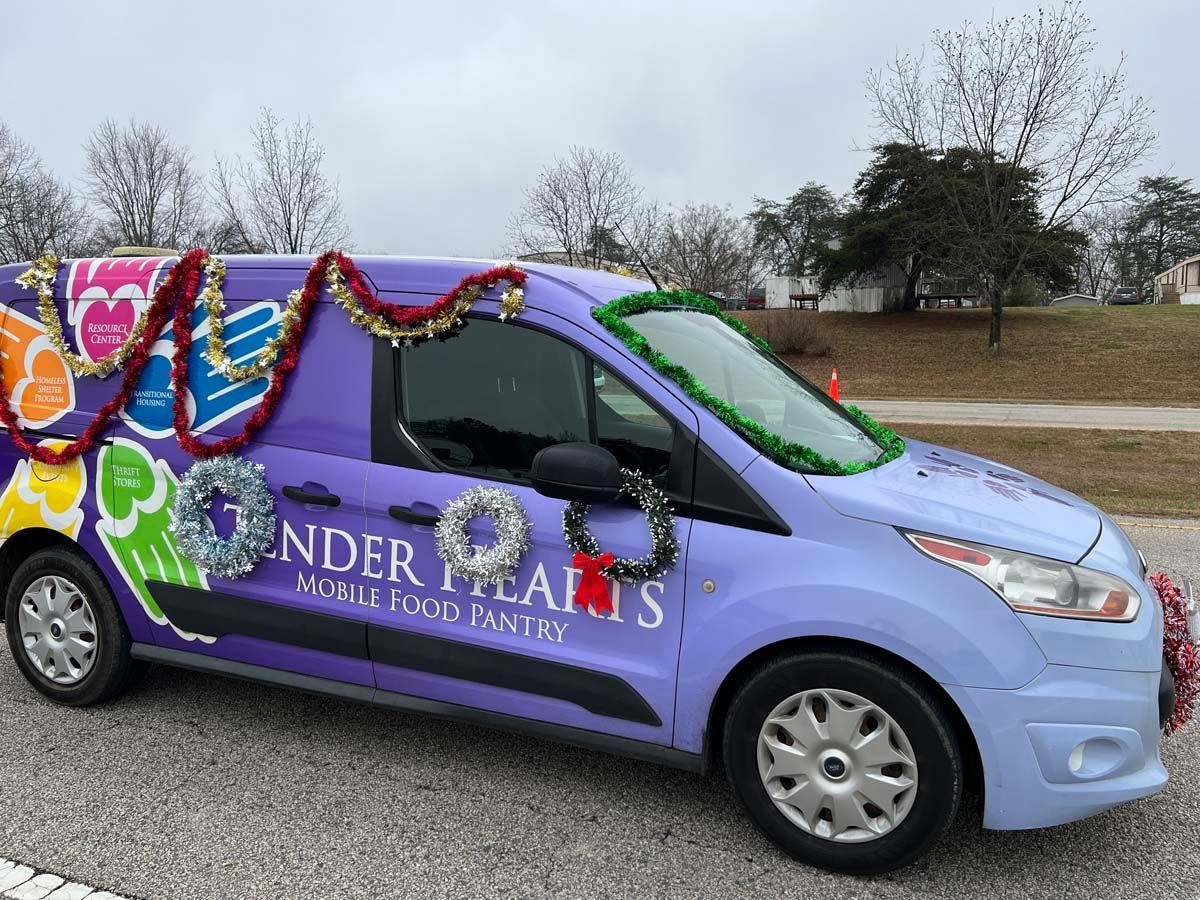 Purple decorated car with floral garlands and signs, parked outdoors on a cloudy day