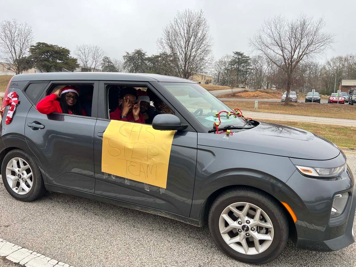 Gray SUV decorated for a parade with people waving from the windows