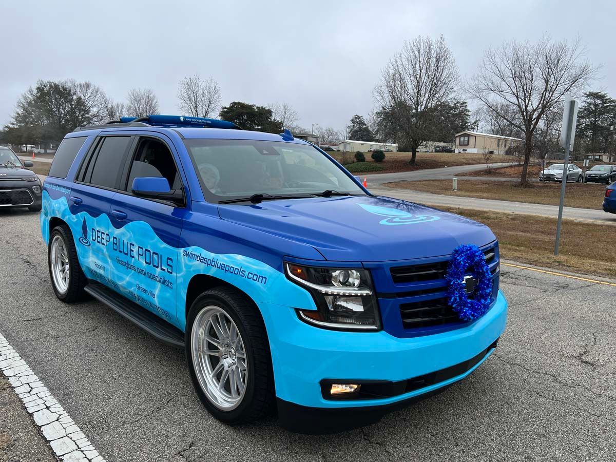Blue and black SUV with company graphics parked on a roadside in winter