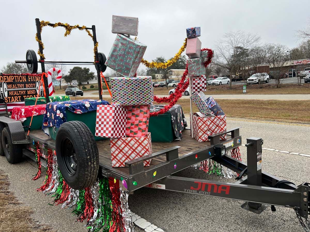 Decorated trailer float with wrapped gift boxes and garlands, parked roadside during a parade