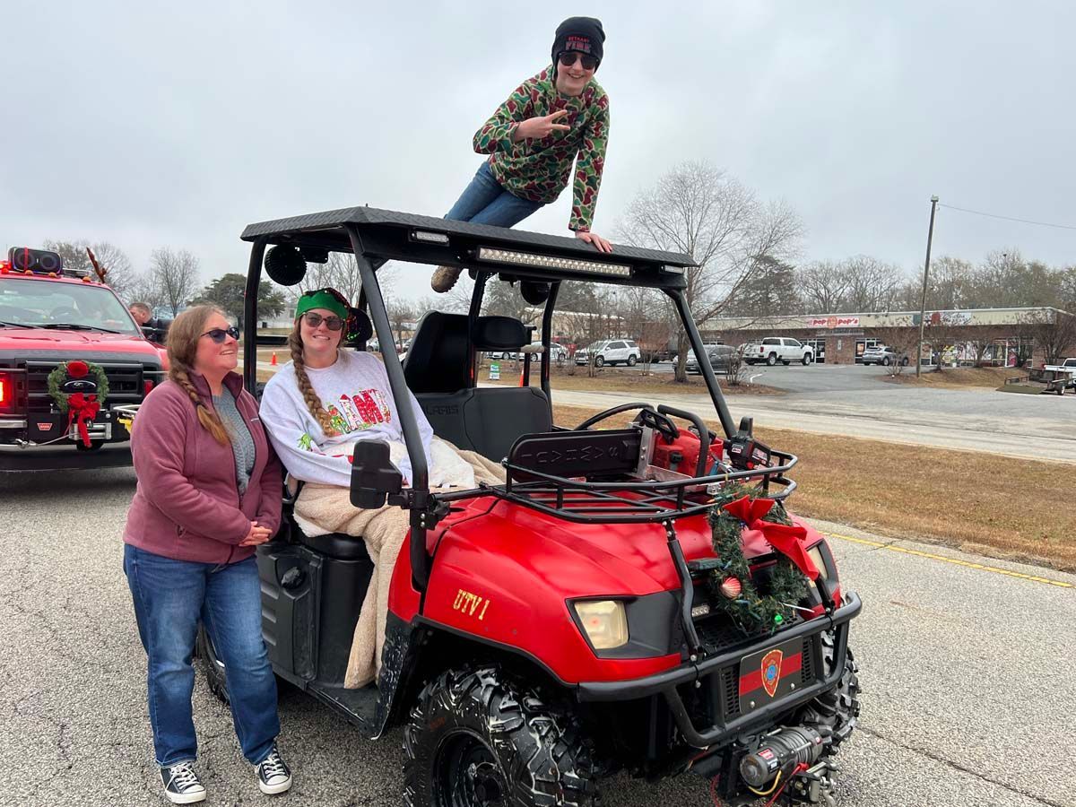 People posing on a red ATV off-road near a road, with one person standing on the roof rack.