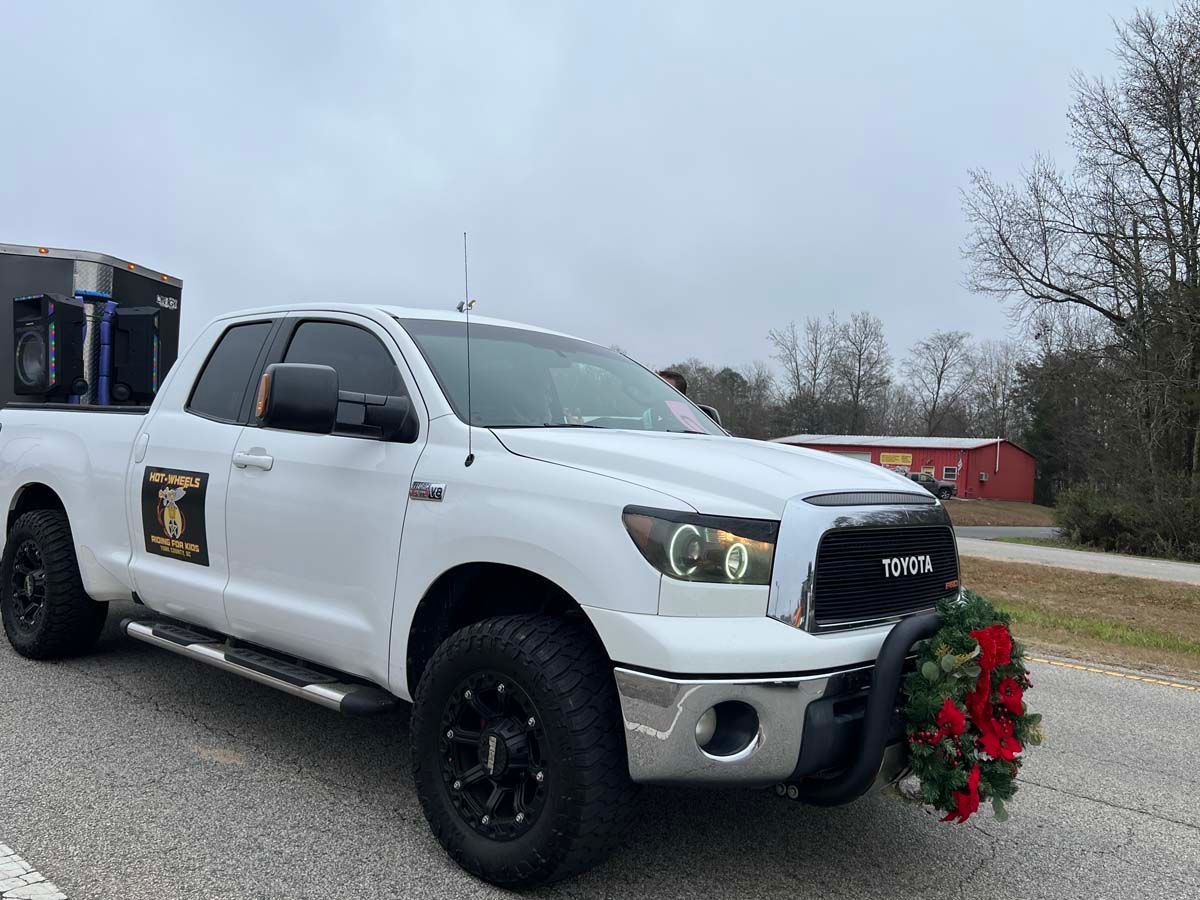 White pickup truck with a wreath on the front, parked by the road in winter
