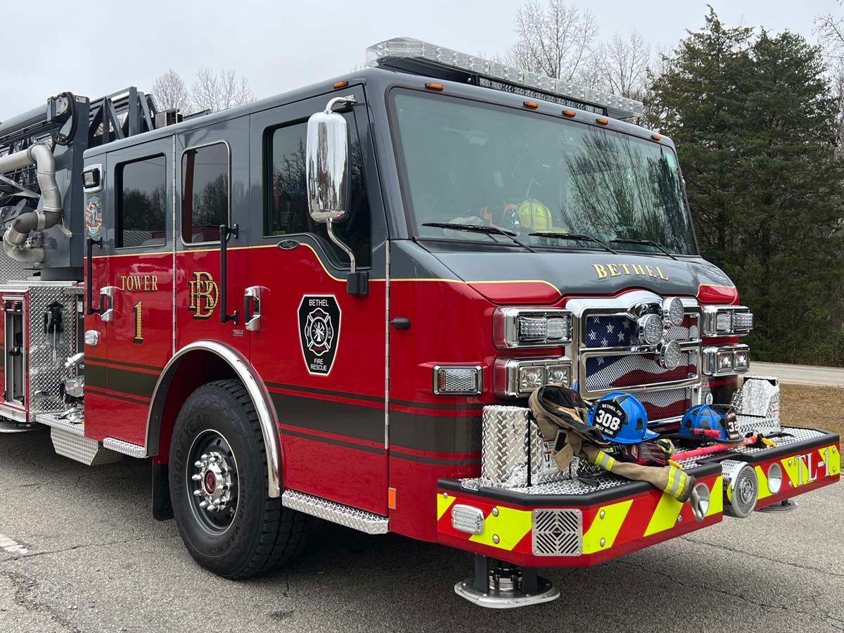 Red fire truck parked outdoors, front view with reflective stripes and equipment on the bumper