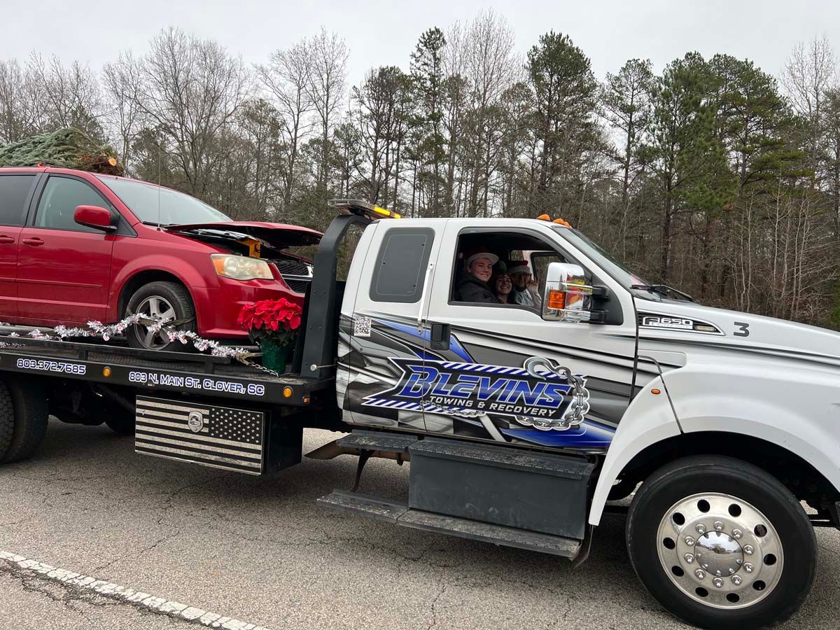 Tow truck carrying a red car on a flatbed beside a white pickup on a road