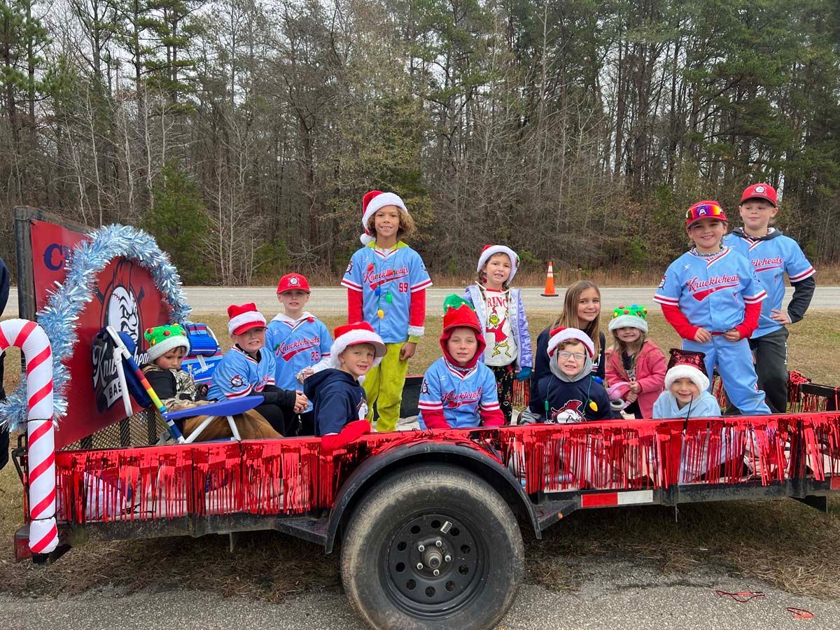 Children in red, white, and blue outfits on a decorated float outdoors near trees