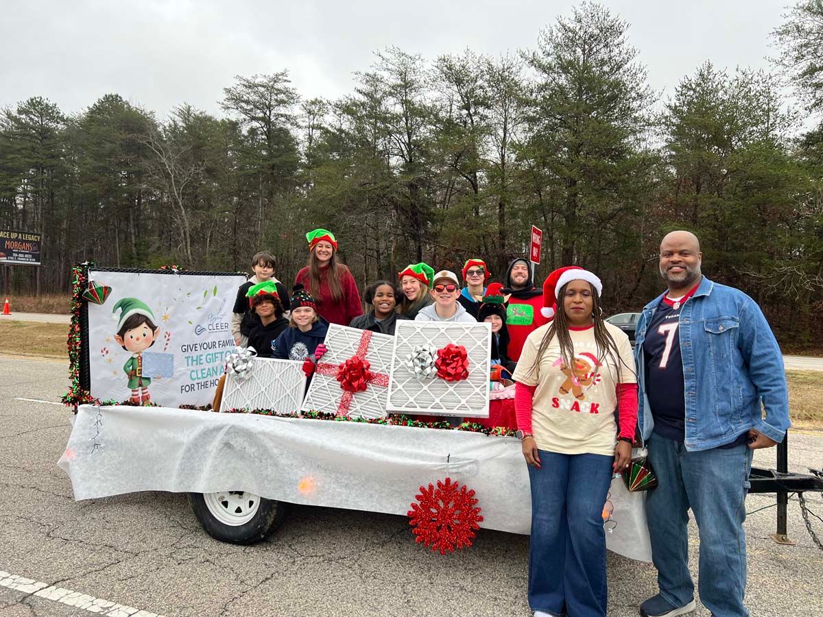 People posing beside a decorated parade float with white and red holiday decorations in a park.
