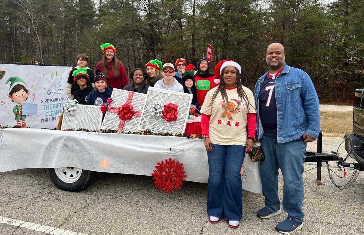 People posing on a decorated parade float with holiday wreaths and red bows