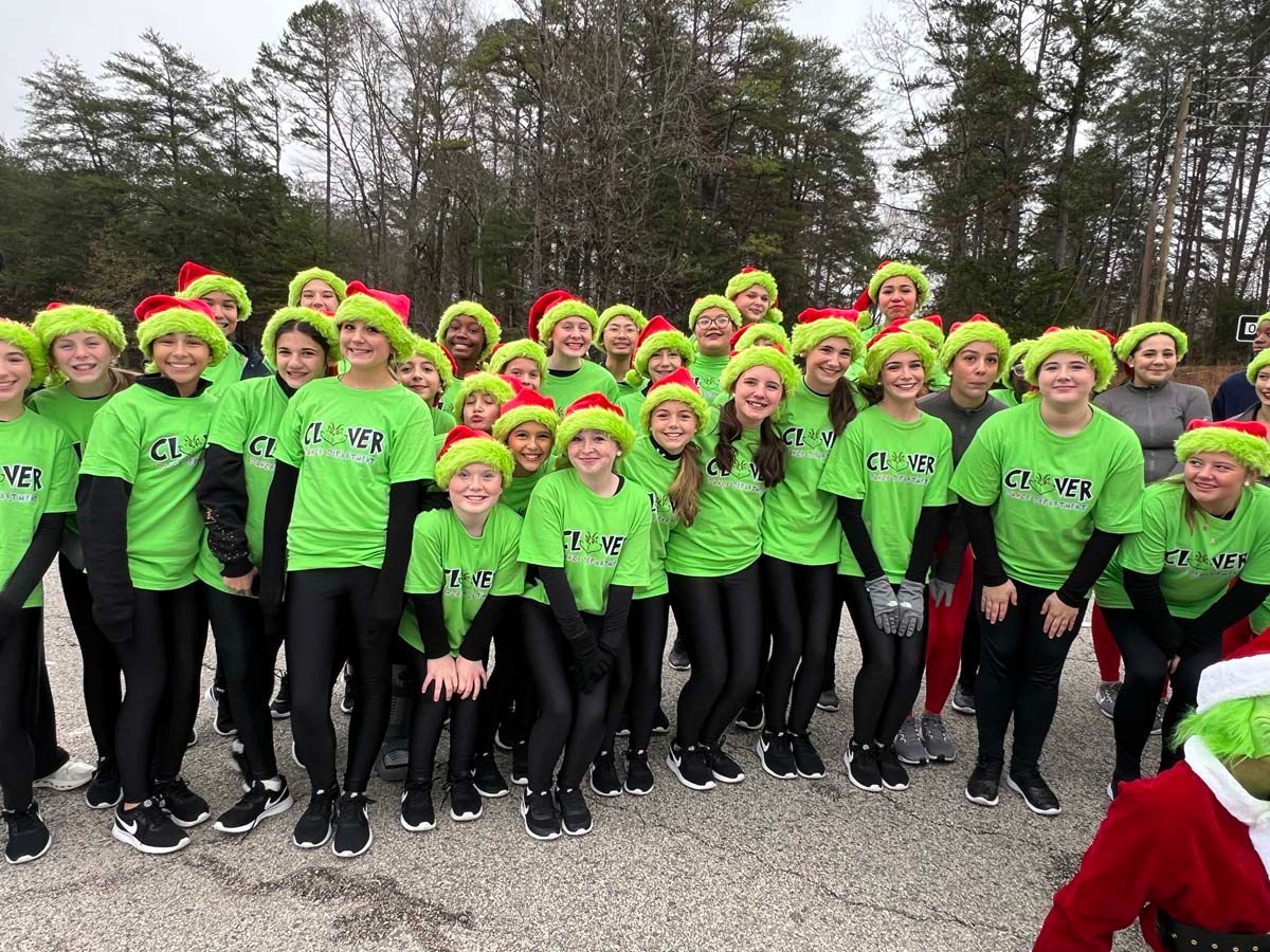 Group of runners in neon green shirts and red hats posing outdoors on a paved path