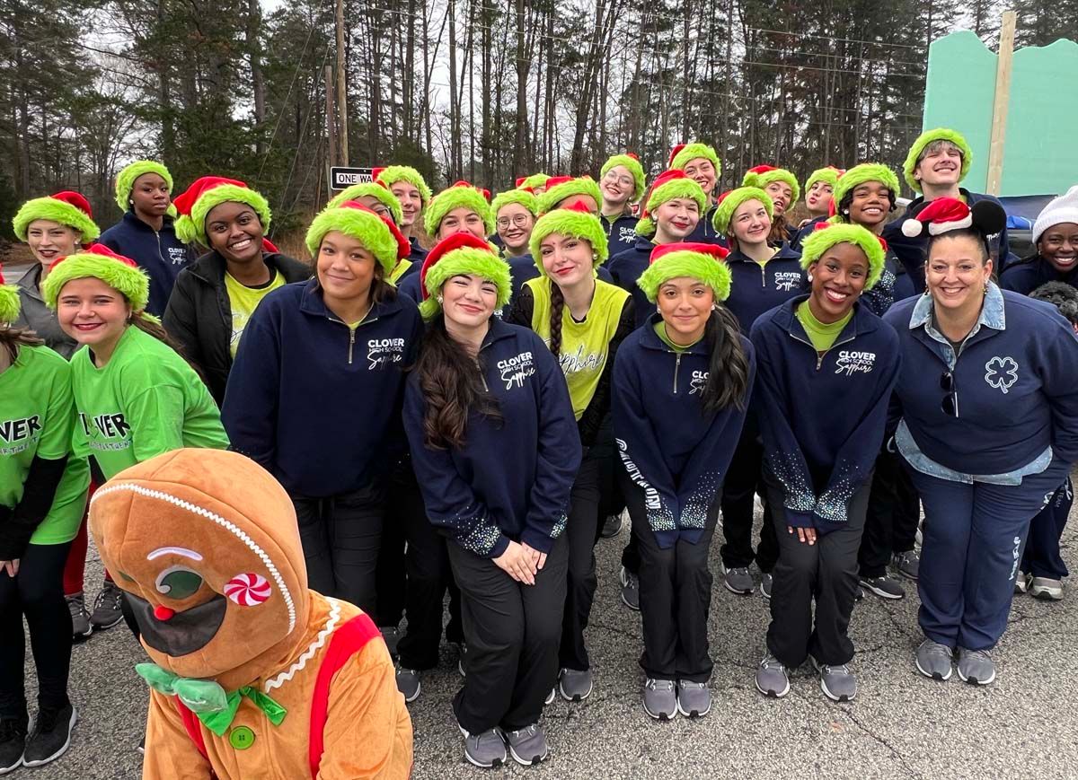 Group of people in neon hats posing outdoors in winter, with a person in a turkey costume in front