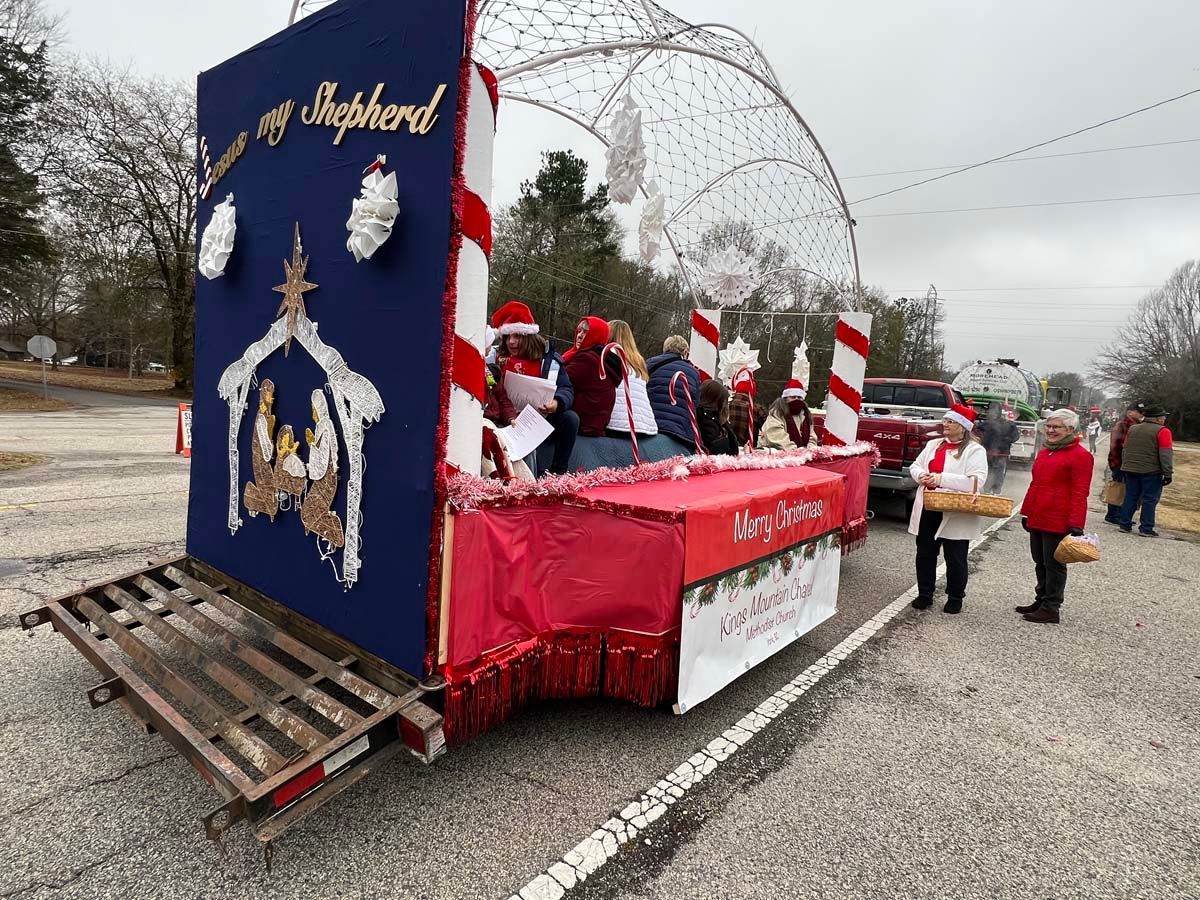 Holiday parade float with red-and-white decorations and people riding in Santa hats