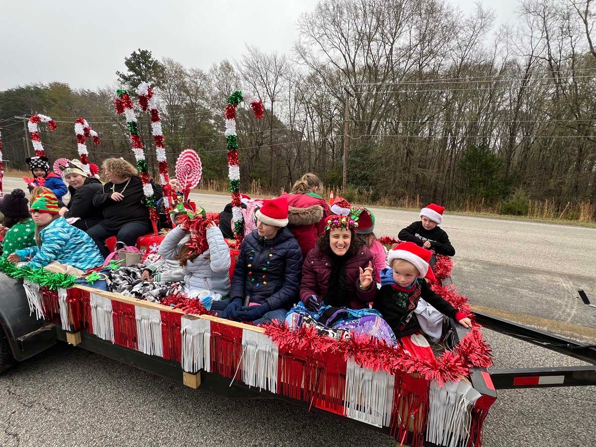 Children in Santa hats riding a decorated holiday float with red, white, and green streamers