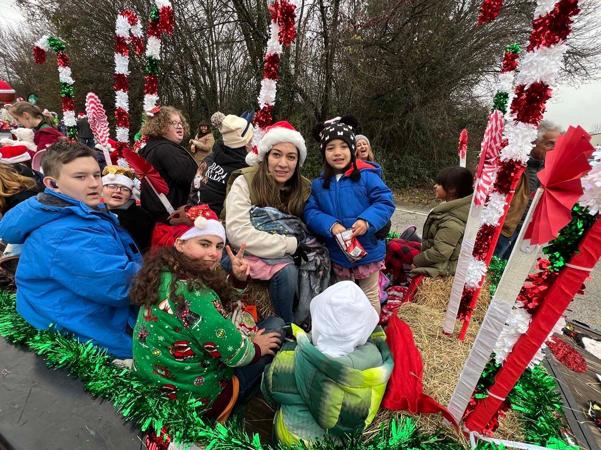 People gathered outdoors beside red-and-white holiday decorations and candy cane poles.