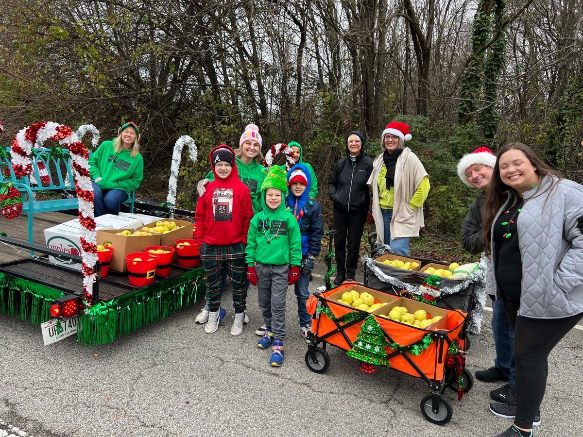 Group beside decorated carts with produce and holiday decorations in a park setting