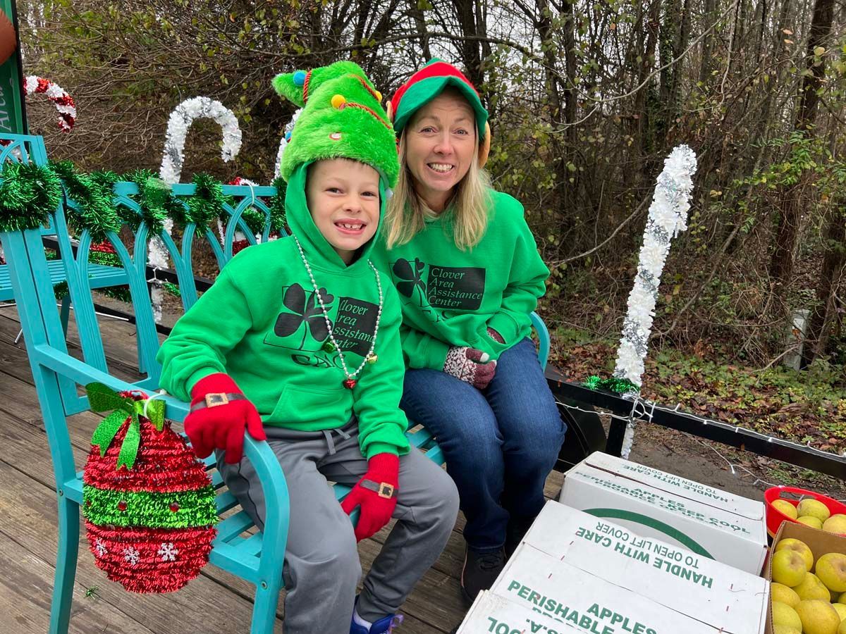 Smiling pair in green holiday outfits sitting on a decorated wagon with apples outdoors