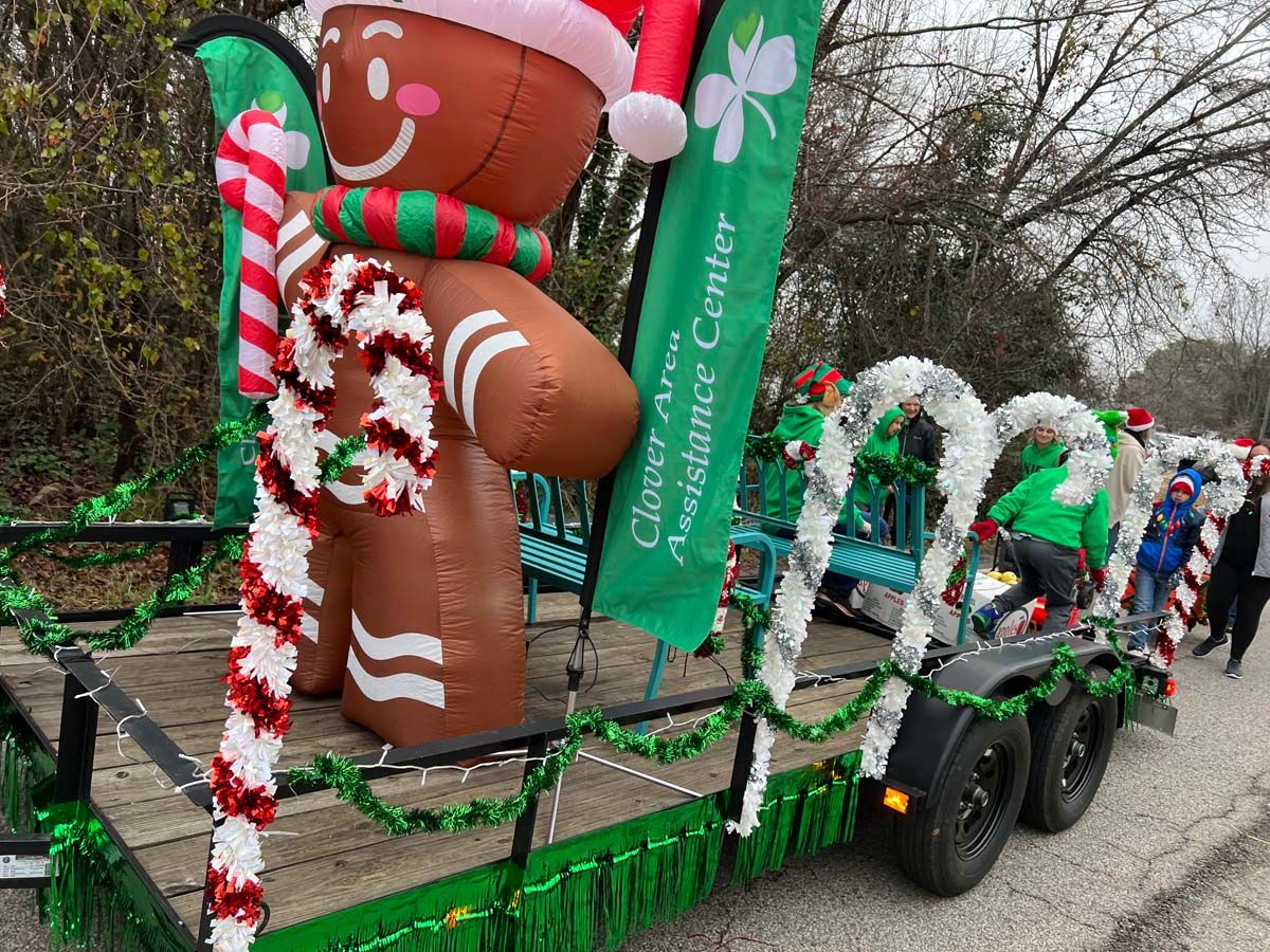 Holiday parade float with giant gingerbread men, candy cane decorations, and green garlands on a trailer.