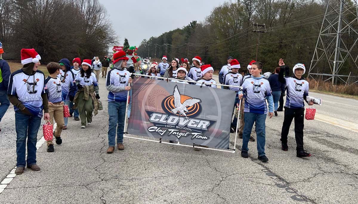 Group of people in white shirts and Santa hats holding a banner on a road during a winter event