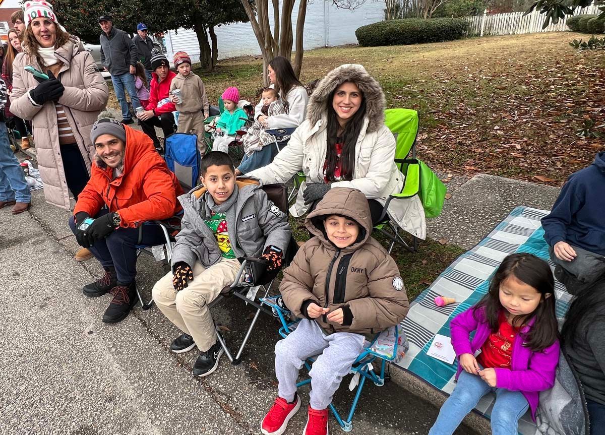 People seated on folding chairs outdoors, bundled in winter coats during a public event