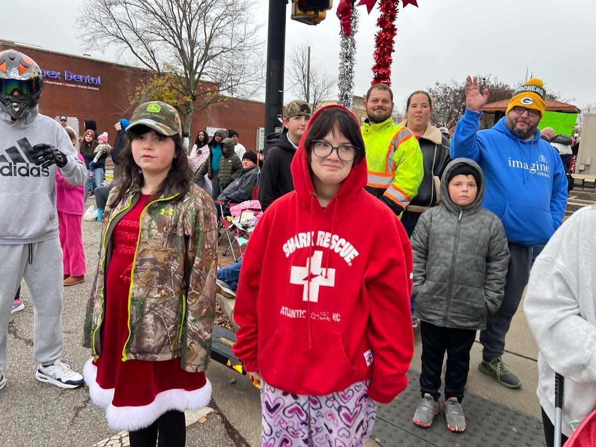People in red, camouflage, and winter clothes standing together outdoors at a parade or rally