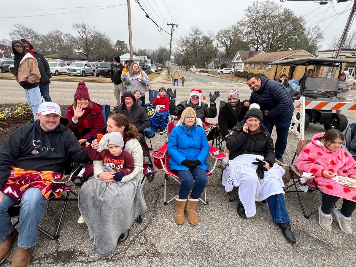 People seated on folding chairs outdoors at a winter community gathering, wrapped in blankets and coats.