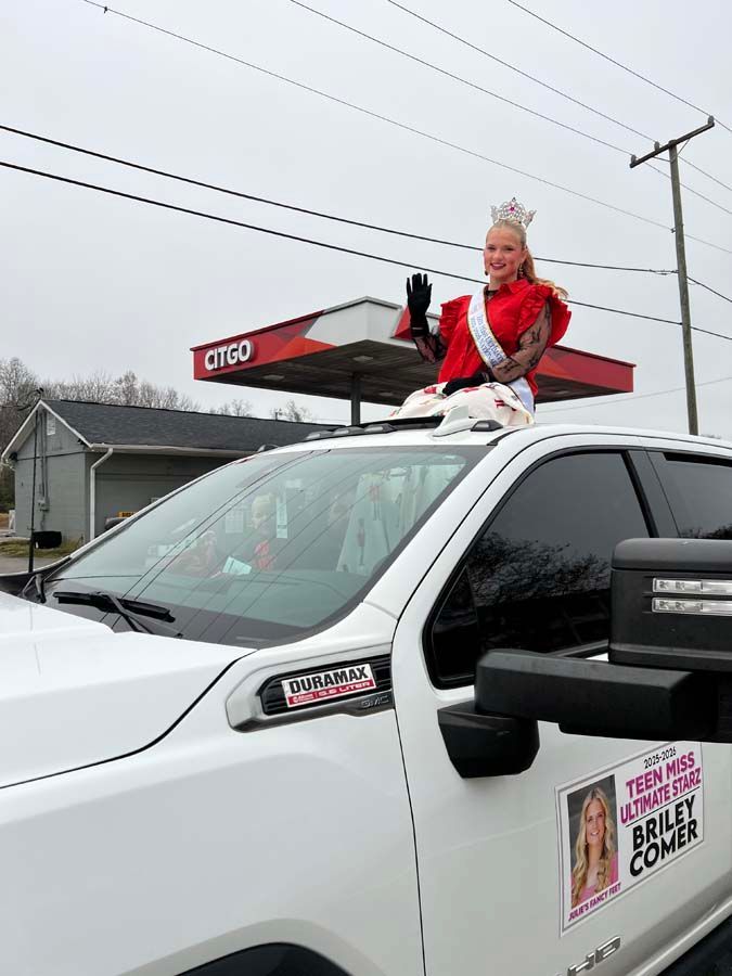 Person in a red jacket sits on a white SUV with a Texas Bank & Trust sign behind them.