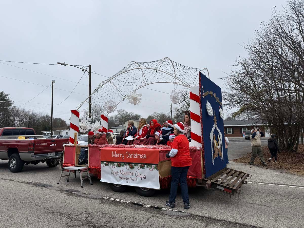 Christmas parade float with Santa, red-and-white decorations, and a sign reading “Merry Christmas”