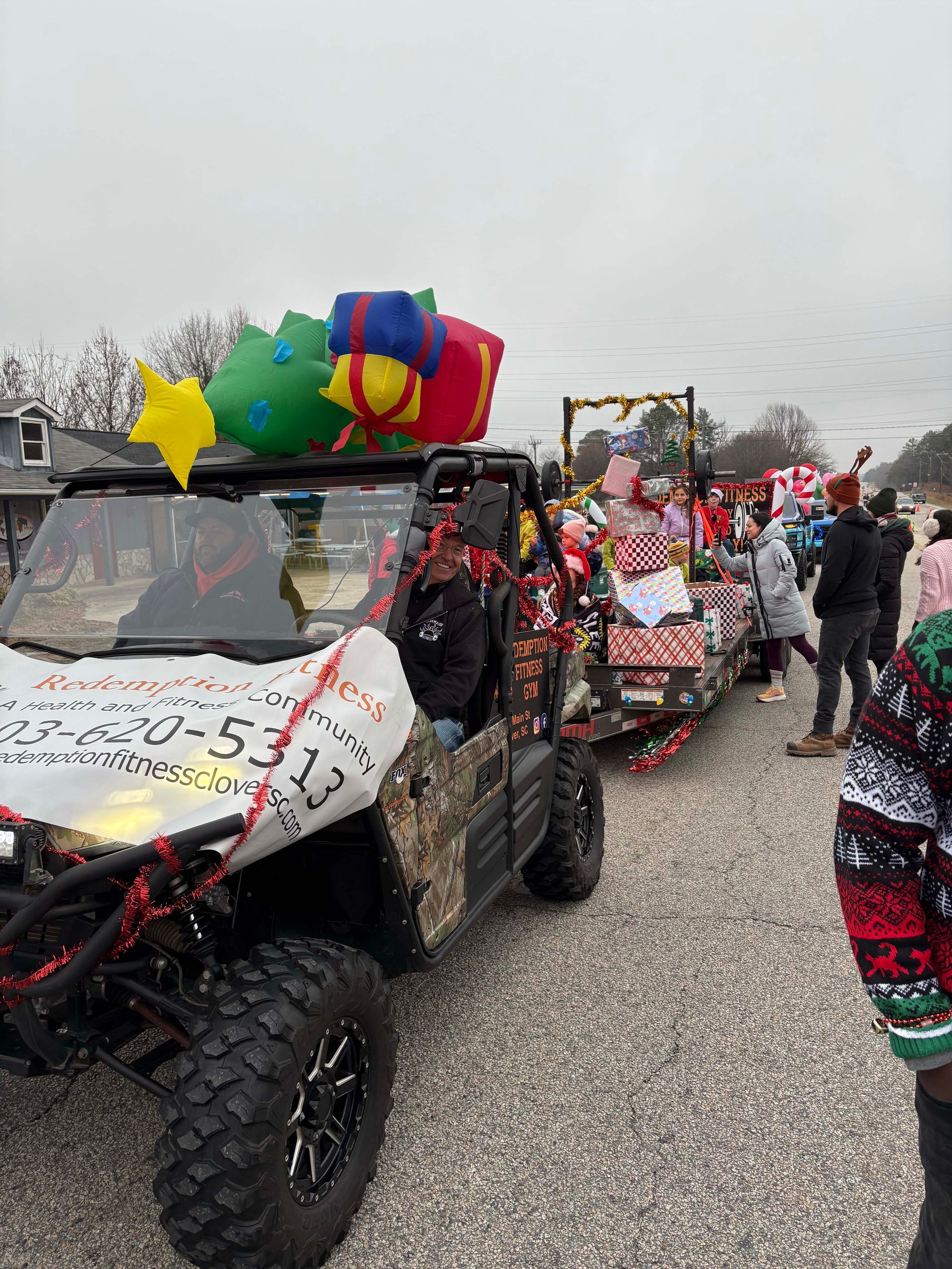 Decorated off-road parade vehicles lined up on a street, one with colorful balloons and a banner.