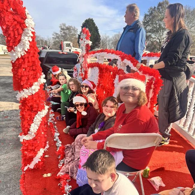 Children in Santa hats seated on a red holiday parade float with candy cane decorations