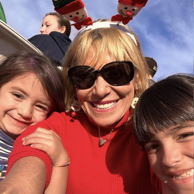 Smiling group selfie with red sweaters and reindeer antlers against a blue sky