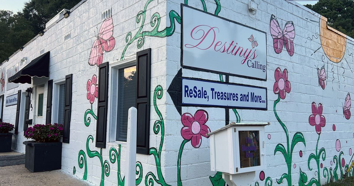 A brightly painted white brick building with a sign for