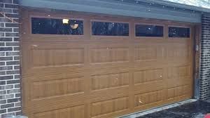 A Wooden Garage Door with Three Windows on A Brick Building - Rochester Hills, MI - J & B Doors