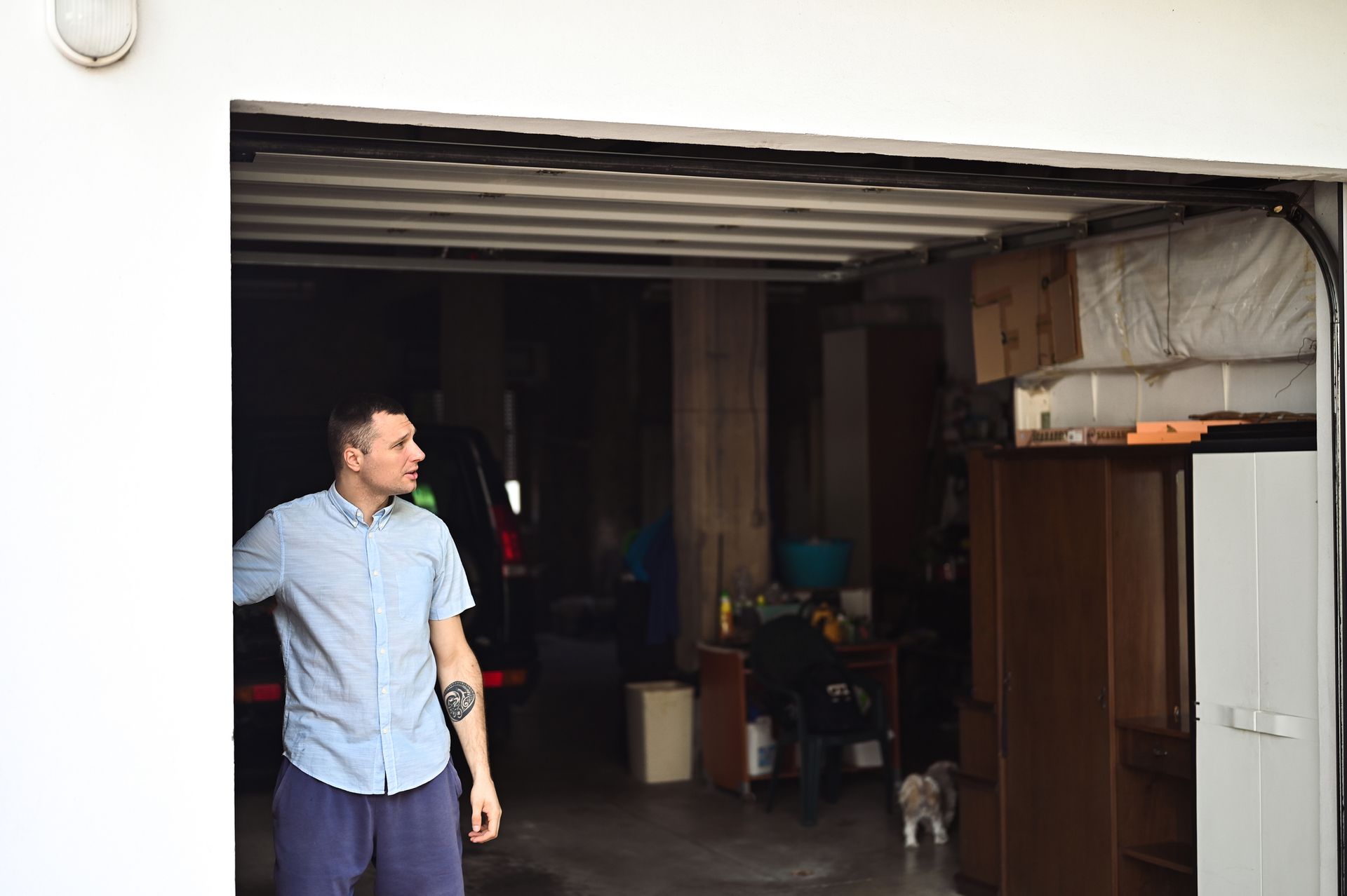 A Man Is Standing in A Garage with His Arms Outstretched - Rochester Hills, MI - J & B Doors