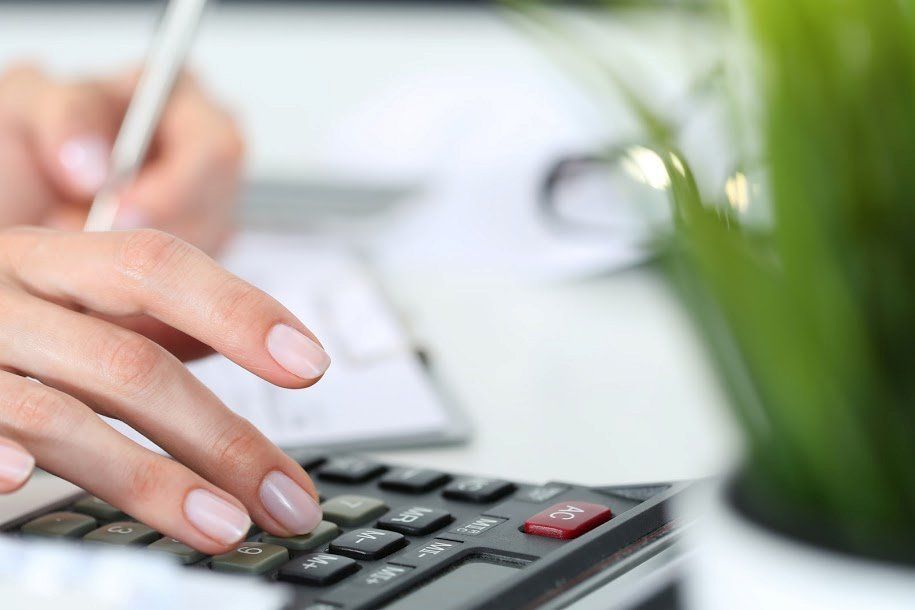 A Woman Is Using a Calculator and Writing on A Piece of Paper - Rochester Hills, MI - J & B Doors