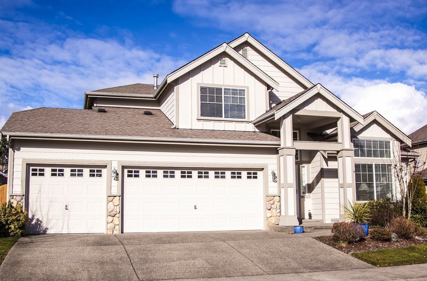A Large White House with Two Garage Doors and A Driveway - Rochester Hills, MI - J & B Doors