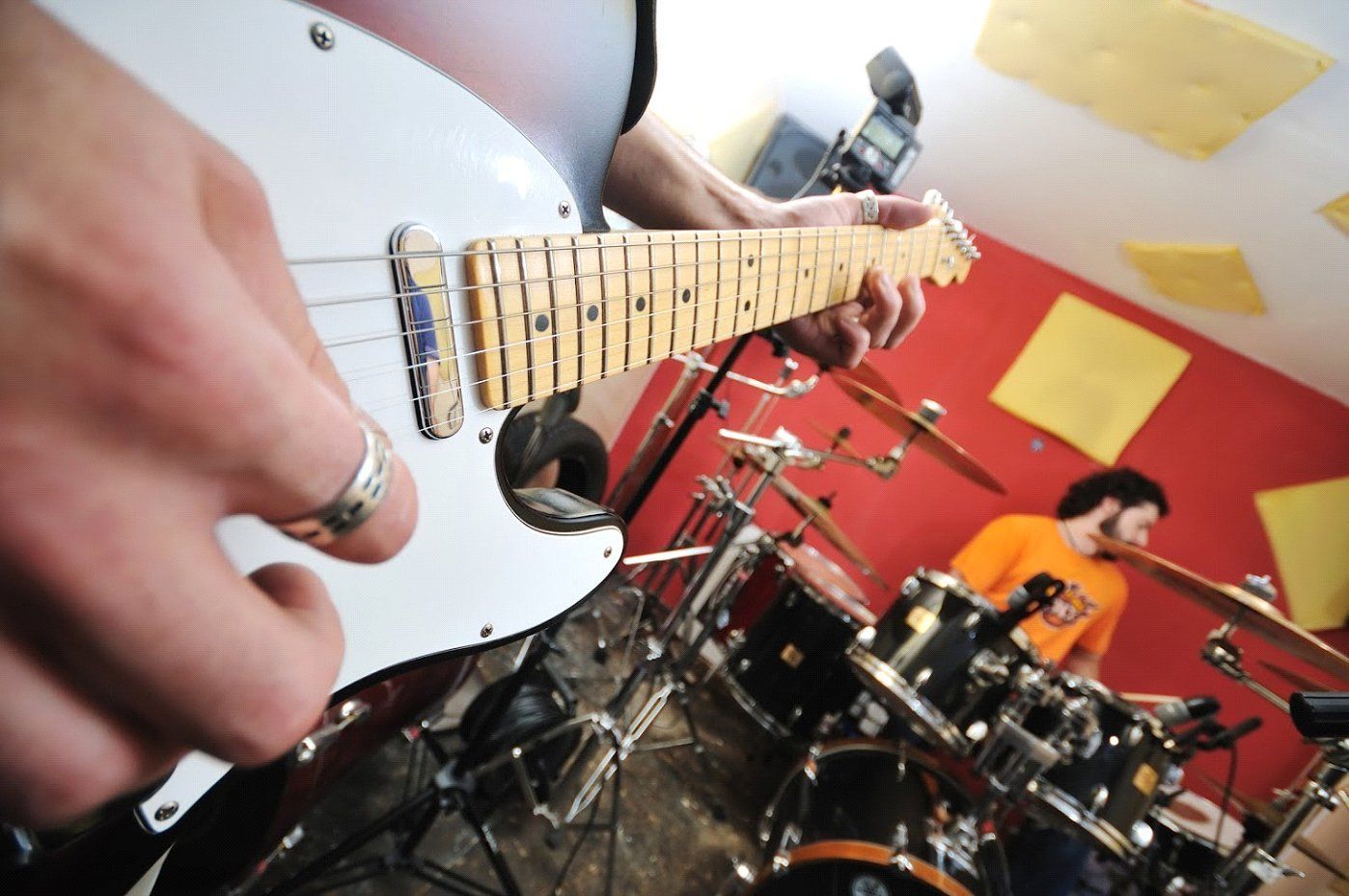 A Man Is Playing an Electric Guitar in Front of A Drum Set - Rochester Hills, MI - J & B Doors