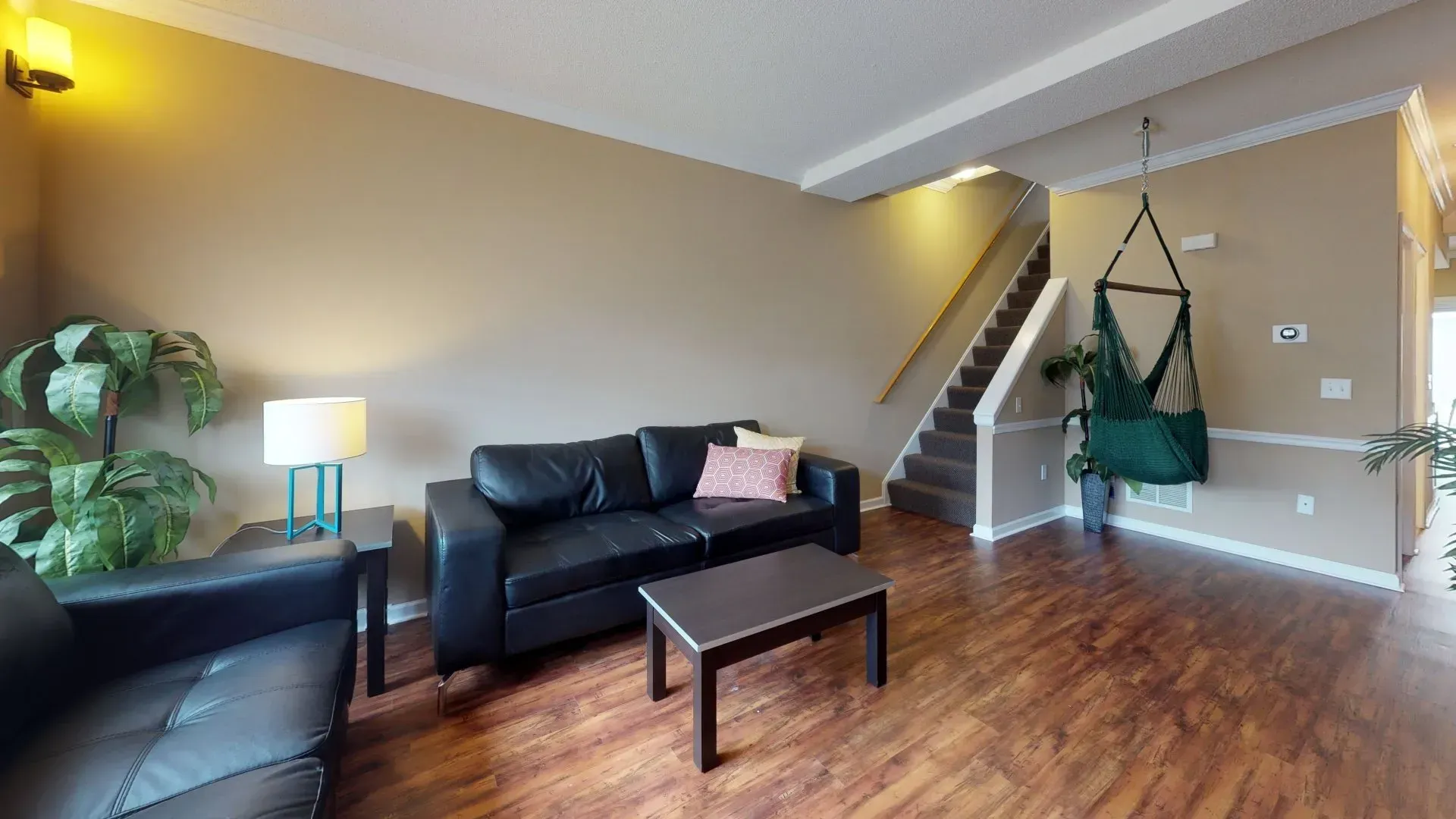 A living room with a couch , chair , coffee table and stairs.